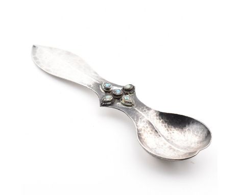 An Arts and Crafts white metal and turquoise caddy spoon. The spoon having planished decoration with cinquefoil turquoise mou