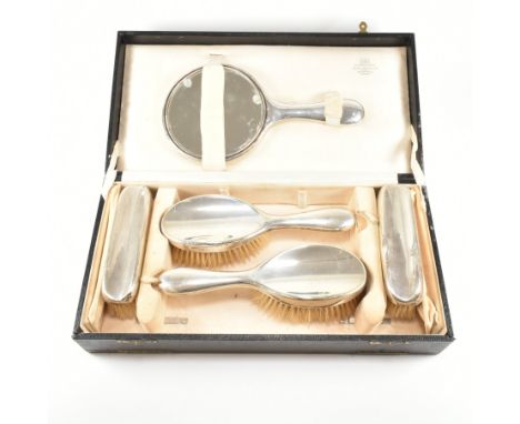 A set of hallmarked silver George V Art Deco vanity items. The lot to include a pair of silver backed hair brushes, a silver 