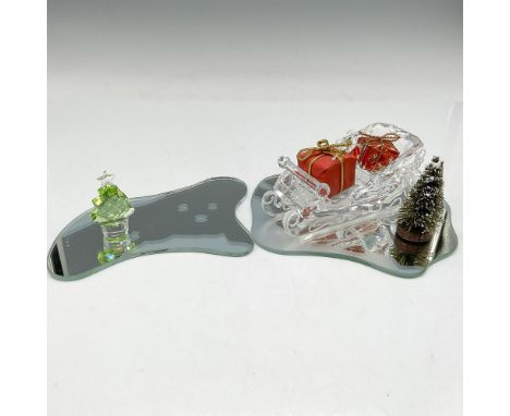 Clear crystal sleigh with presents sitting on mirrored glass with accent tree. Additional crystal green tree on separate mirr