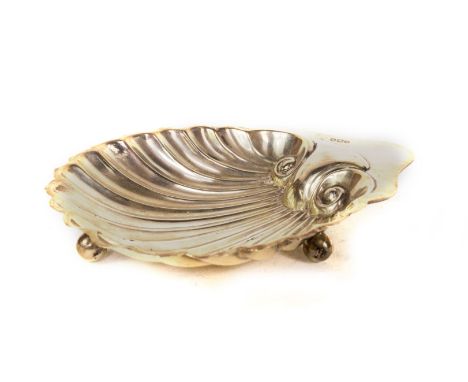 A George V silver shell butter dish, of traditional scallop design with plain thumb piece, and raised upon three ball feet, S