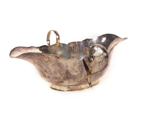 An Edwardian small silver two handled sauce boat, with wavy border and shaped with two pourers and plain query handles, raise