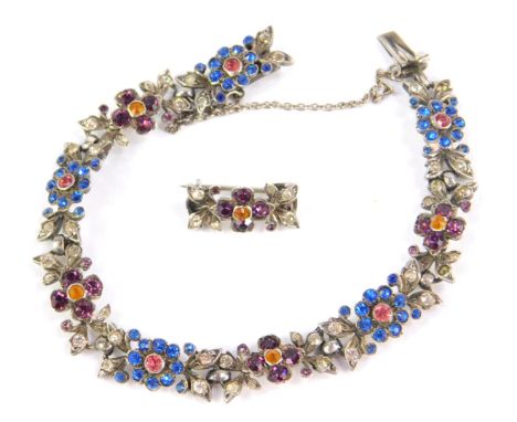 A silver floral bracelet and brooch set, with design of blue, purple, orange and white paste stones, with flower and leaf des