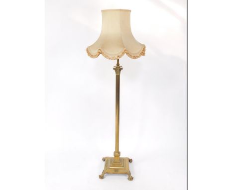 An early 20thC brass standard lamp, of Corinthian column design raised on a stepped square base on four claw feet, fitted for