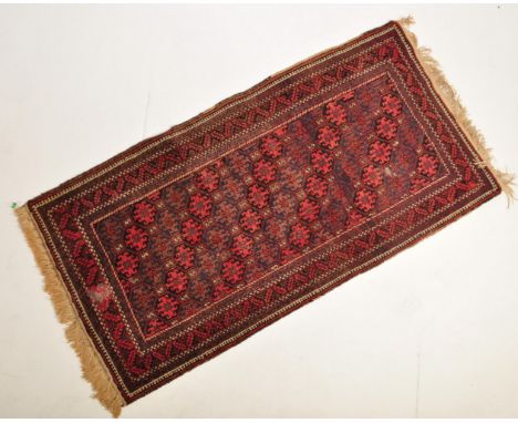 A 20th century Persian Islamic rug / carpet having a repeating geometric pattern atop a red background set within a&nbsp; geo