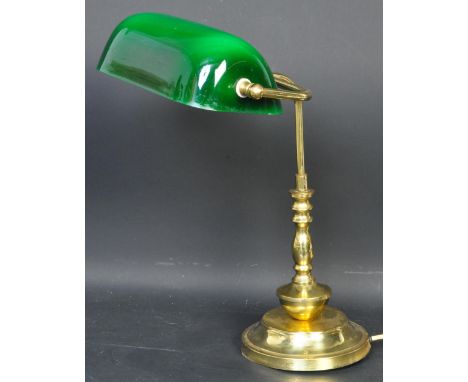 A vintage retro mid 20th century style brass bankers lamp having green glass swinging shade raised upon a brass circular step