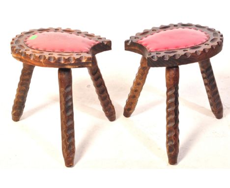 A pair of vintage 20th century Spanish hardwood carved milking stools. Each stool having a horse shoe shaped seat with leathe