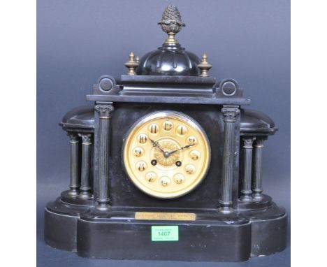 An early 20th century slate mantel clock of architectural form having an acorn finial top over a reeded dome, brass clock fac
