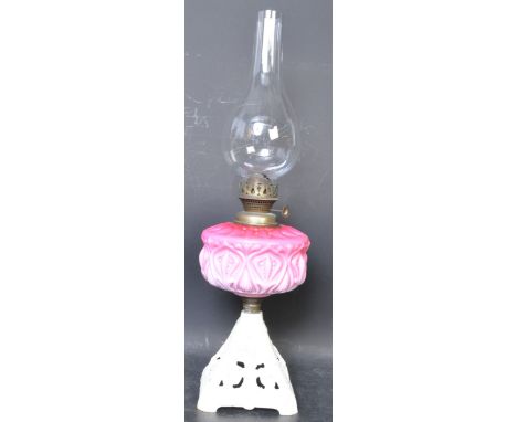 A Victorian circa 1900 oil / paraffin lamp having an ovoid flue, peach opaline glass reservoir raised on a pierced cast iron 