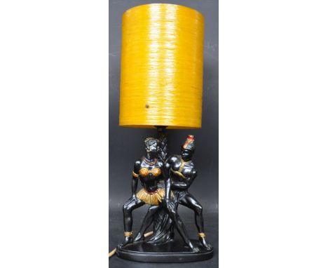 A retro vintage circa 1960s mid 20th century Blackamoor lamp having two dancing figures raised on an oval base. The lamp havi