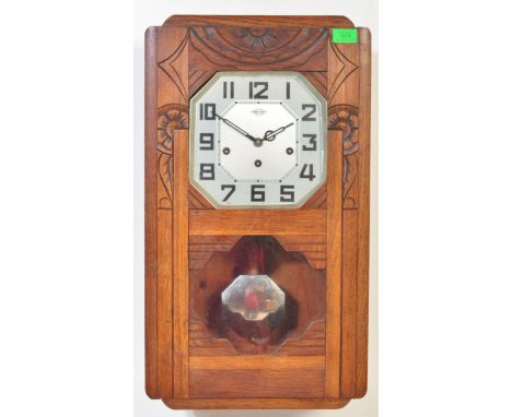 A vintage 20th Century Art Deco oak cased hanging wall clock having a carved door with silvered dial having Arabic numeral ch