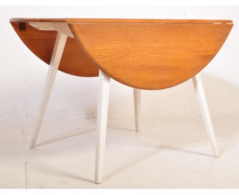 A retro vintage mid 20th century Ercol beech drop leaf dining table having a chamfered edge to the circular table top raised 