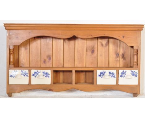 A vintage 20th century pine plate rack having a flared top with hooded area&nbsp;supported by columns and ceramic drawers bel