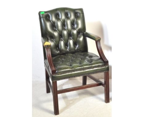 A vintage 20th century green leather and wood frame Gainsborough chair having shaped elbow rests raised over square supports 