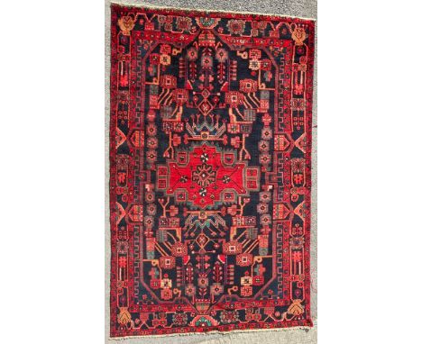 An early 20th century hand knotted Persian Islamic Nahawand floor rug carpet. The rug having a central red medallion with geo