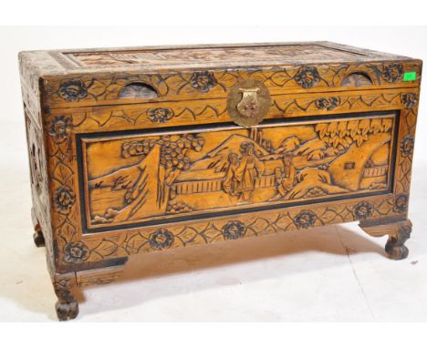 A mid 20th century Chinese Oriental hardwood trunk having profuse carvings throughout raised on ball and claw feet.
