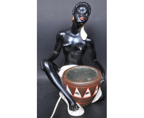 A retro vintage mid 20th century circa 1960s lamp of a seated African lady holding a drum. The uplight lamp being situated wi