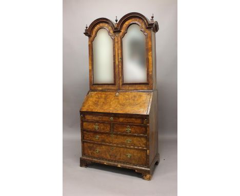 A GEORGE I WALNUT DOUBLE DOME TOPPED BUREAU BOOKCASE. The double domed top with deep moulding and turned finials above twin m