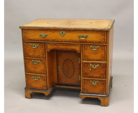 A GEORGE III SATINWOOD VENEERED KNEEHOLE DESK. The desk elaborately veneered, the top with radiating veneers and central oval