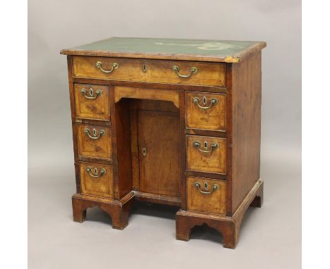 A GEORGE II WALNUT KNEEHOLE DESK, the leather top above one long drawer and an arrangement of six drawers either side of the 
