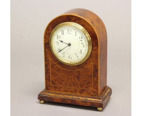 AN EDWARDIAN BURR MAPLE VENEERED MANTLE CLOCK. With a circular white enamelled dial with arabic numerals, with a single train