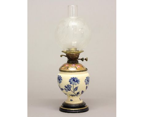 A VICTORIAN OIL LAMP AND SHADE. A Victorian oil lamp with a ceramic base decorated with blue daisies against a cream ground, 