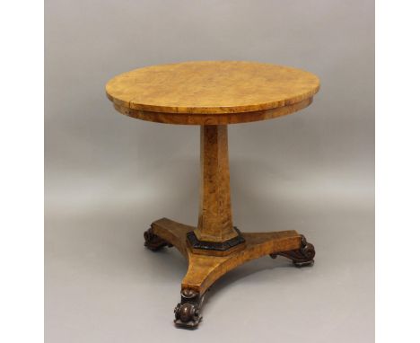 A GEORGE IV BURR MAPLE OCCASIONAL TABLE. With a circular top on tapering hexagonal column and triform platform with leaf carv