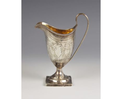 A George III silver cream jug, London 1796, of helmet form on square base with loop handle, chased with floral swags, the cen