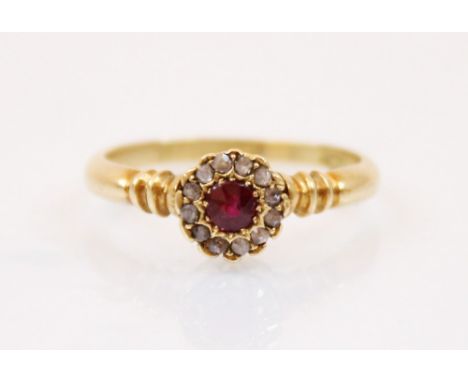 An Edwardian ruby and diamond ring, the central round cut ruby surrounded by a border of diamond chips, within a coronet styl
