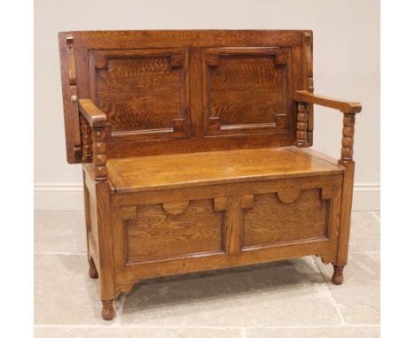 A 17th century style golden oak monks bench, 20th century, the recessed geometric panelled back rest on bobbin turned support