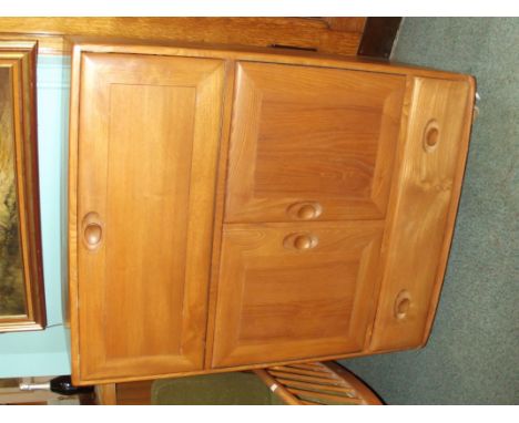 Ercol bureau in light elm, the fall flap above a twin cupboard and single base drawer, carried on castors, height 110cm width