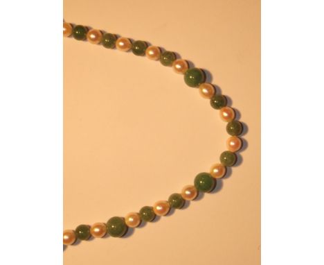 A pearl and jade necklace set in alternate order, laced with string with a sterling silver clasp