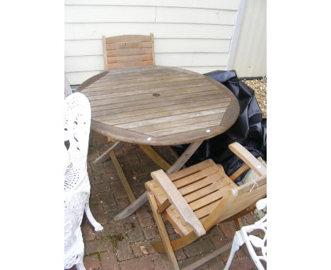 A teak garden circular table - diameter 110cms, together with two chairs and a garden furniture cover