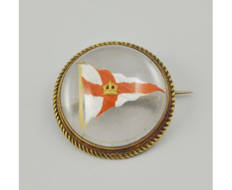 Late 19th Century rock crystal cabochon and yellow metal mounted rope twist bordered, circular brooch, inset with enamel flag