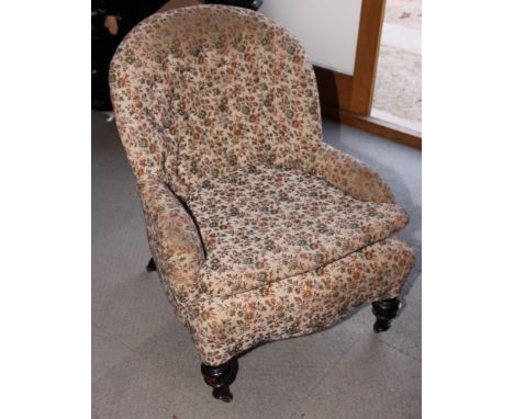 A Victorian tub armchair, upholstered in a floral tapestry, on turned ebonised supports
