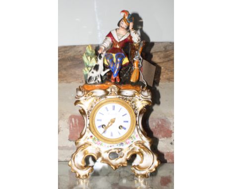 A late 19th Century French mantel clock in flower and gilt decorated porcelain case with surmount formed as a hunter and his 