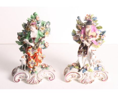 A pair of Samson "Derby" porcelain bocage figures of a lady playing a mandolin and a gentleman with pipes, on scrollwork base