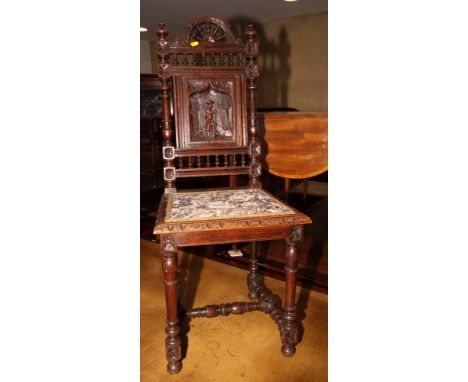 A Victorian single chair, back inset carved panel of a man with a spade, seat upholstered in a floral tapestry, on block turn