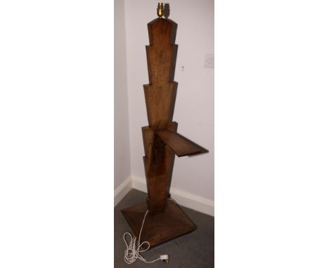 An Art Deco walnut standard lamp with barbed rectangular stem, fitted two small folding shelves, on square base, 58" high