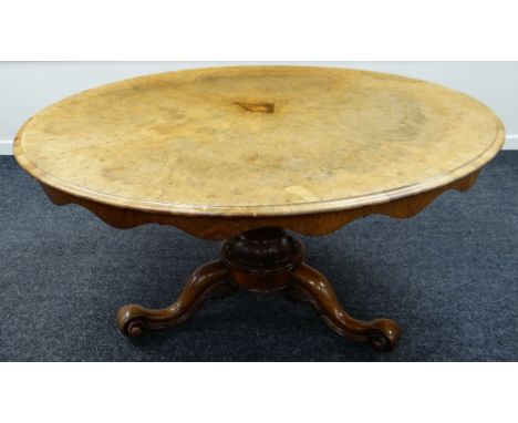 A VICTORIAN BREAKFAST TABLE tilting on a tripod base with scroll supports & heavily carved column and having a wavy frieze, 1
