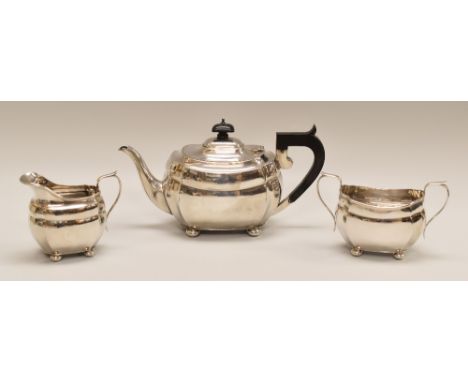 A THREE-PIECE FACETED SILVER TEA SET comprising teapot, cream jug & sugar basin, all of oval form on four corner bun feet, Ch