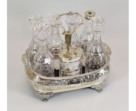A GEORGIAN SILVER CRUET SET of seven bottles and being basin-form on four claw feet and having repousse work all round, Londo