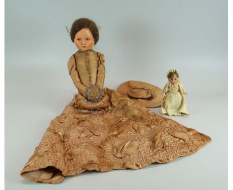 A VICTORIAN PAPIER-MACHE DOLL in long silk dress and bonnet, together with a miniature bisque head doll of the same period Pr