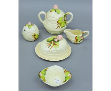 A quantity of Clarice Cliff porcelain tablewares, including a preserve pot, a cream jug a butter dish, a sugar bowl and a bis