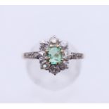 An unmarked gold diamond and emerald flowerhead ring. Ring size L/M.