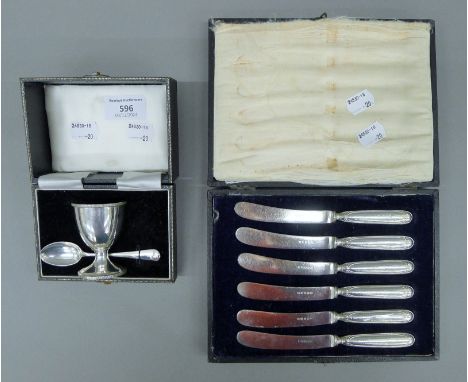 A cased set of silver handled butter knives, and a cased silver egg cup and spoon set. The former case 20.5 cm wide. 