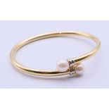 A gold and cultured pearl bangle marked 750. 6.4 cm long, weight 13 grammes.