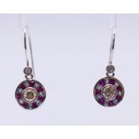 A pair of diamond and gem-set earrings, the brilliant-cut diamond collet,