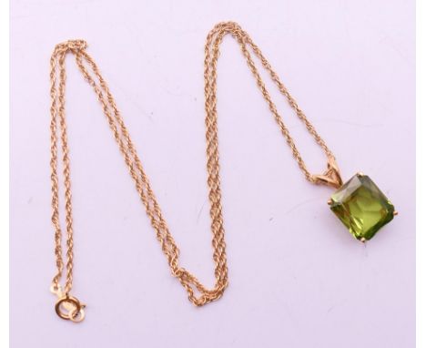 A gold and green stone, possibly peridot, pendant on a 14 K gold chain. The pendant 1.5 cm high. 