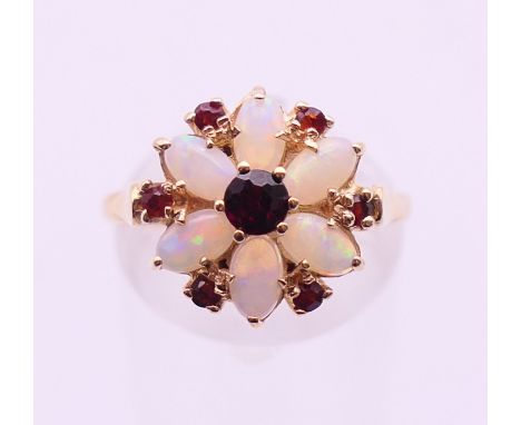 A 9 ct gold opal and garnet flowerhead ring. Ring size N/O. 