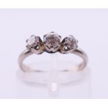 An 18 ct white gold three-stone diamond ring. Ring size H/I.